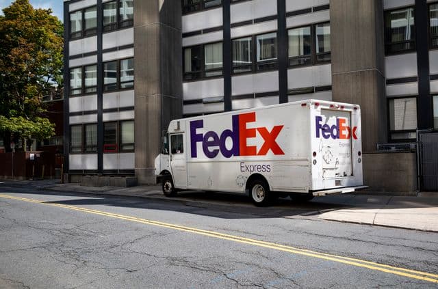 A FedEx delivery truck parked outside a business complex while making a delivery.