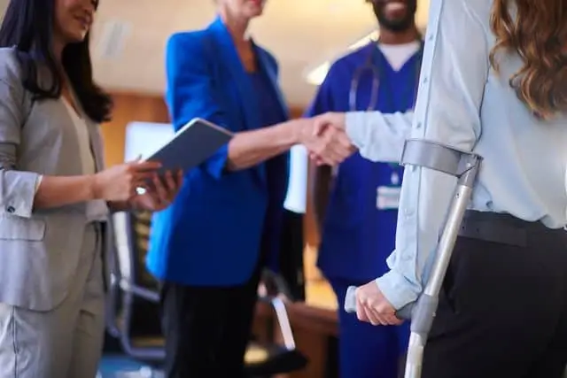 A woman shakes the hand of her slip-and-fall lawyer after getting treatment for her injuries at the hospital.