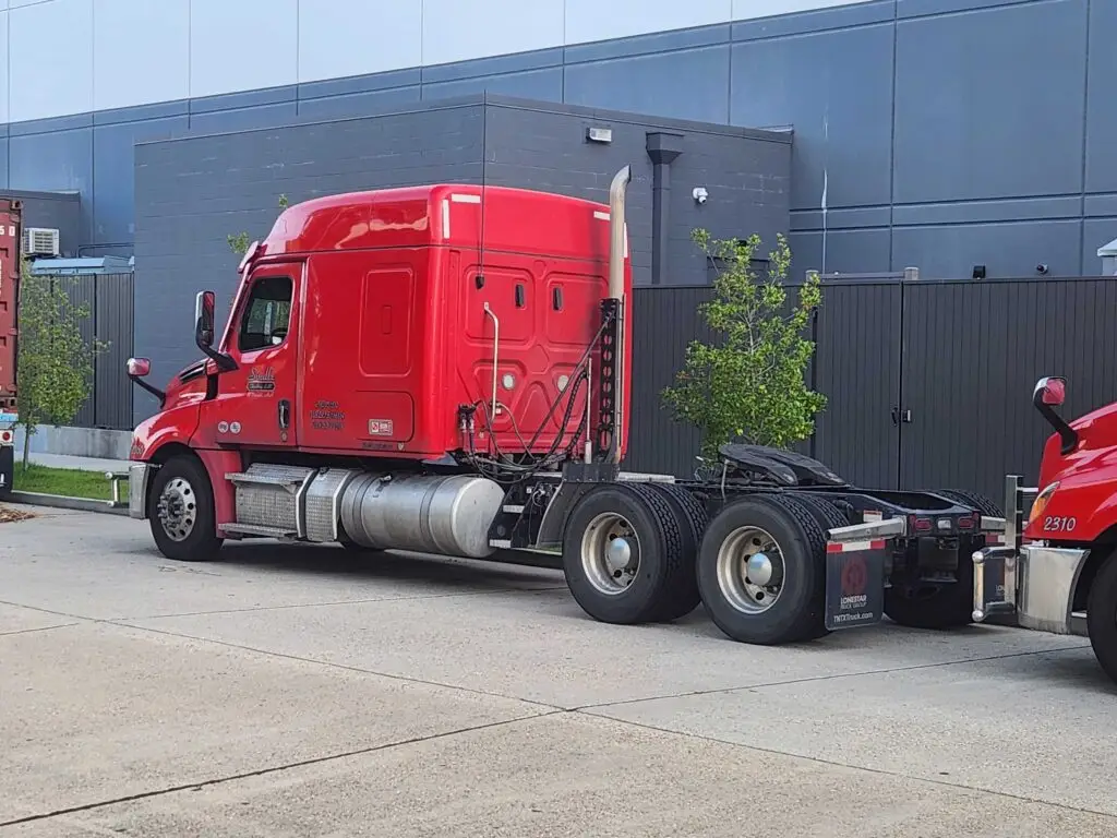 A red truck cab without a trailer attached, know as a bobtail. 