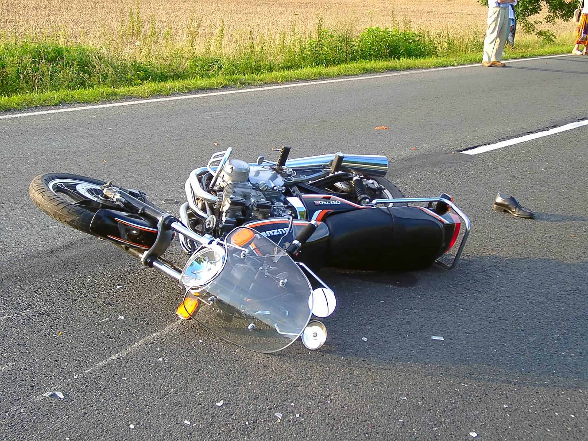 A crashed motorcycle lies in the middle of an Indiana road with debris surrounding it.