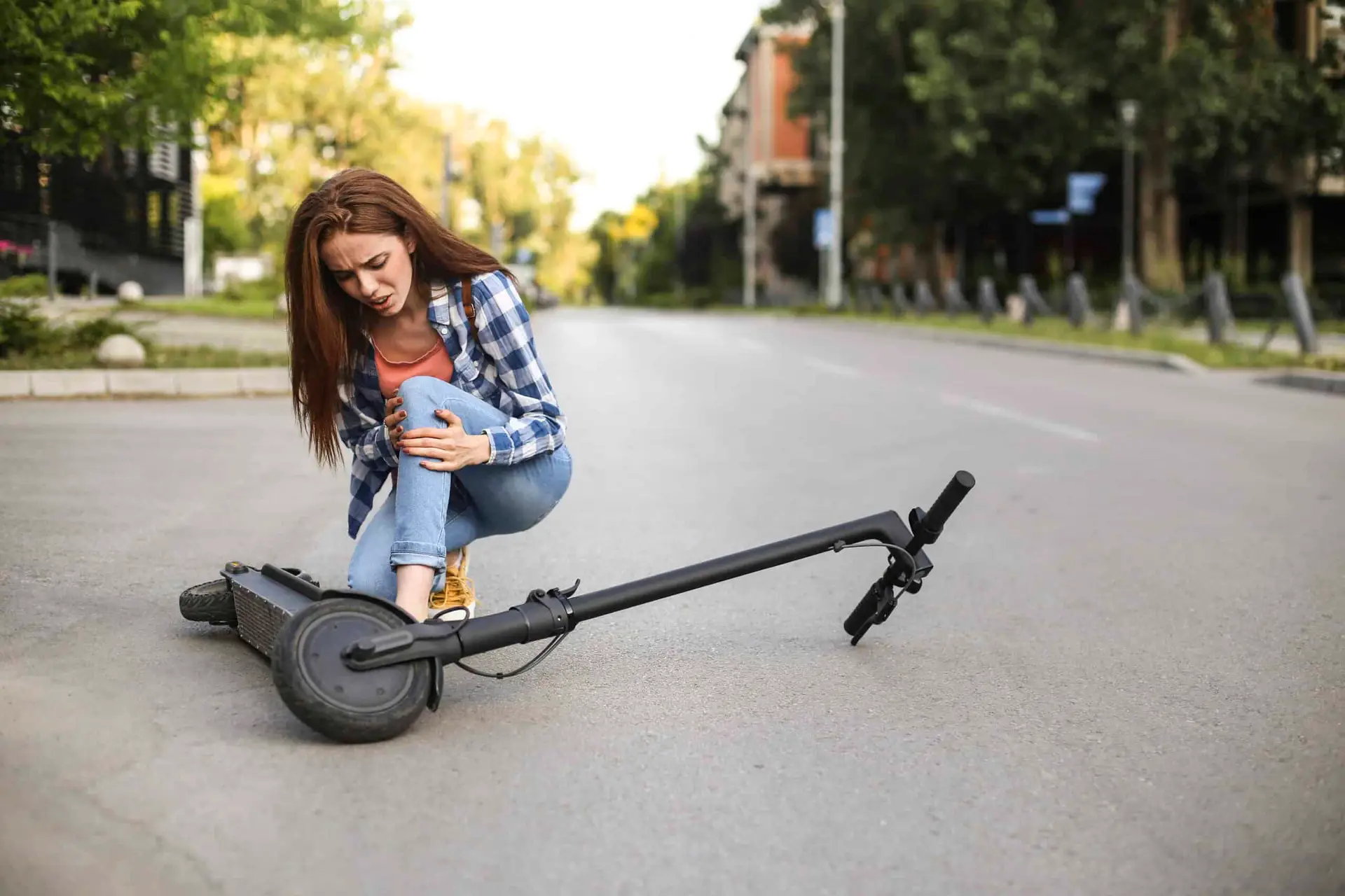 A woman holds her knee in pain after a motorized scooter accident.