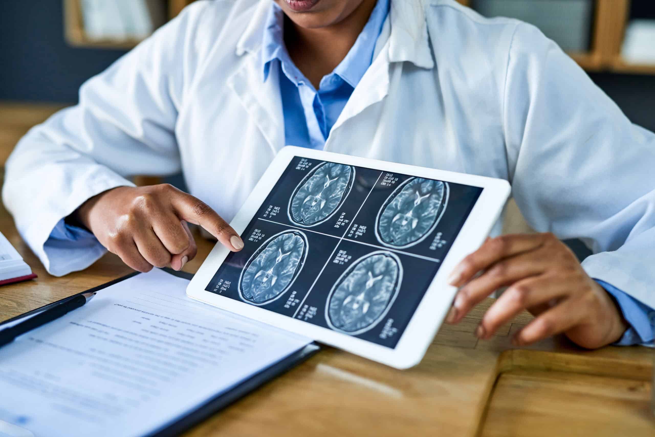 A doctor reviews the results of a brain scan image with a patient who has suffered a brain injury.