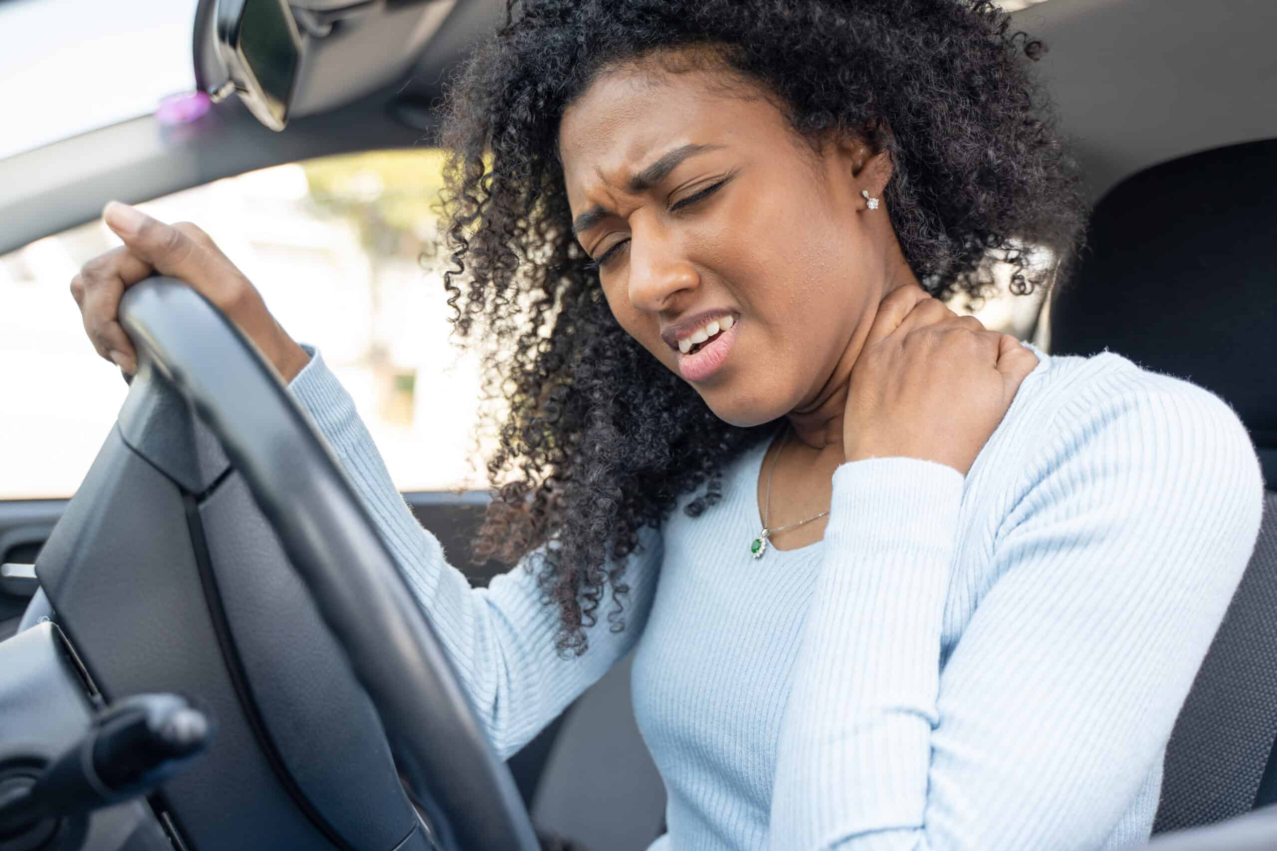A woman grabs her neck and winces in pain after a car accident.