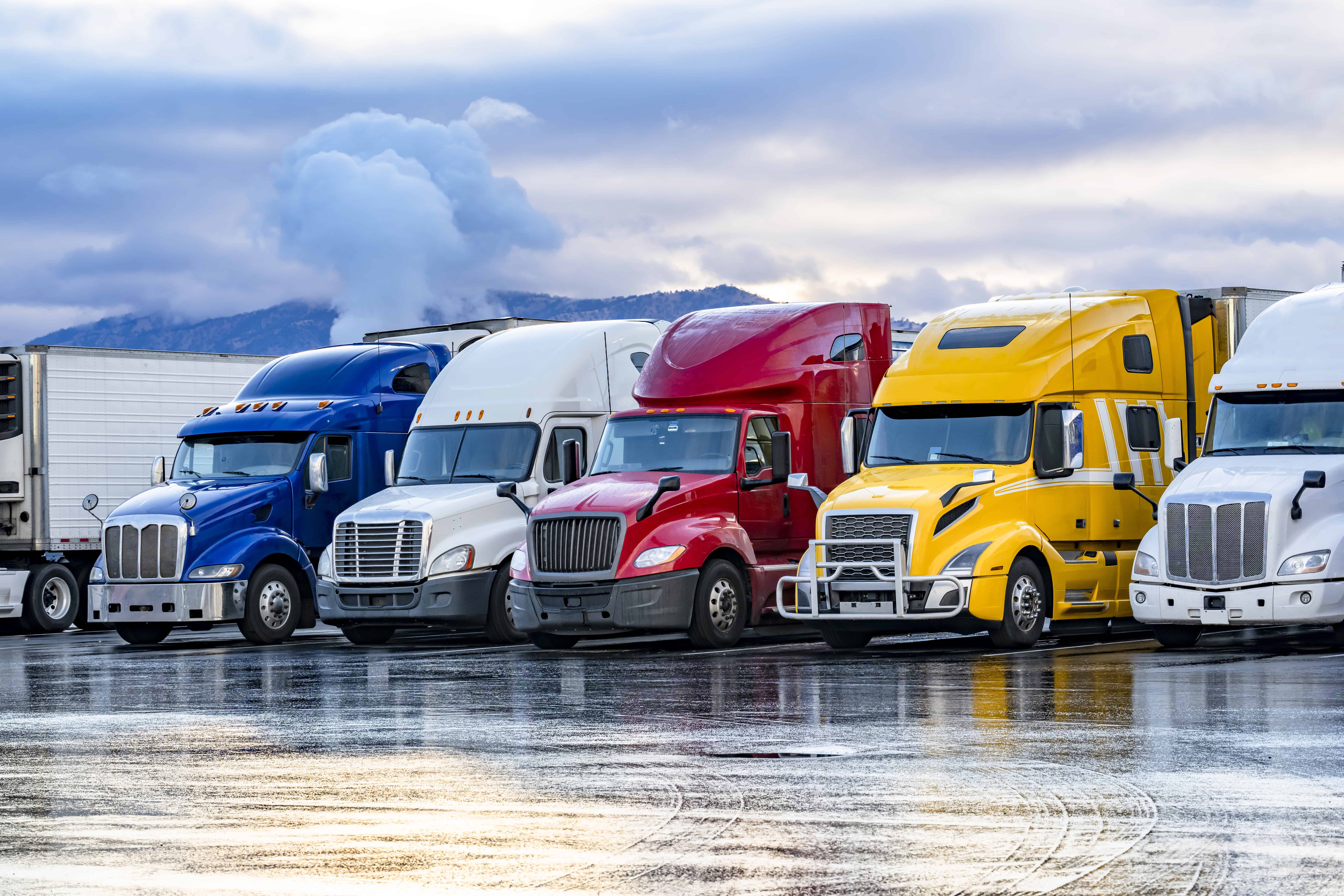 A row of colorful semis parked in a row on a cold winter day.