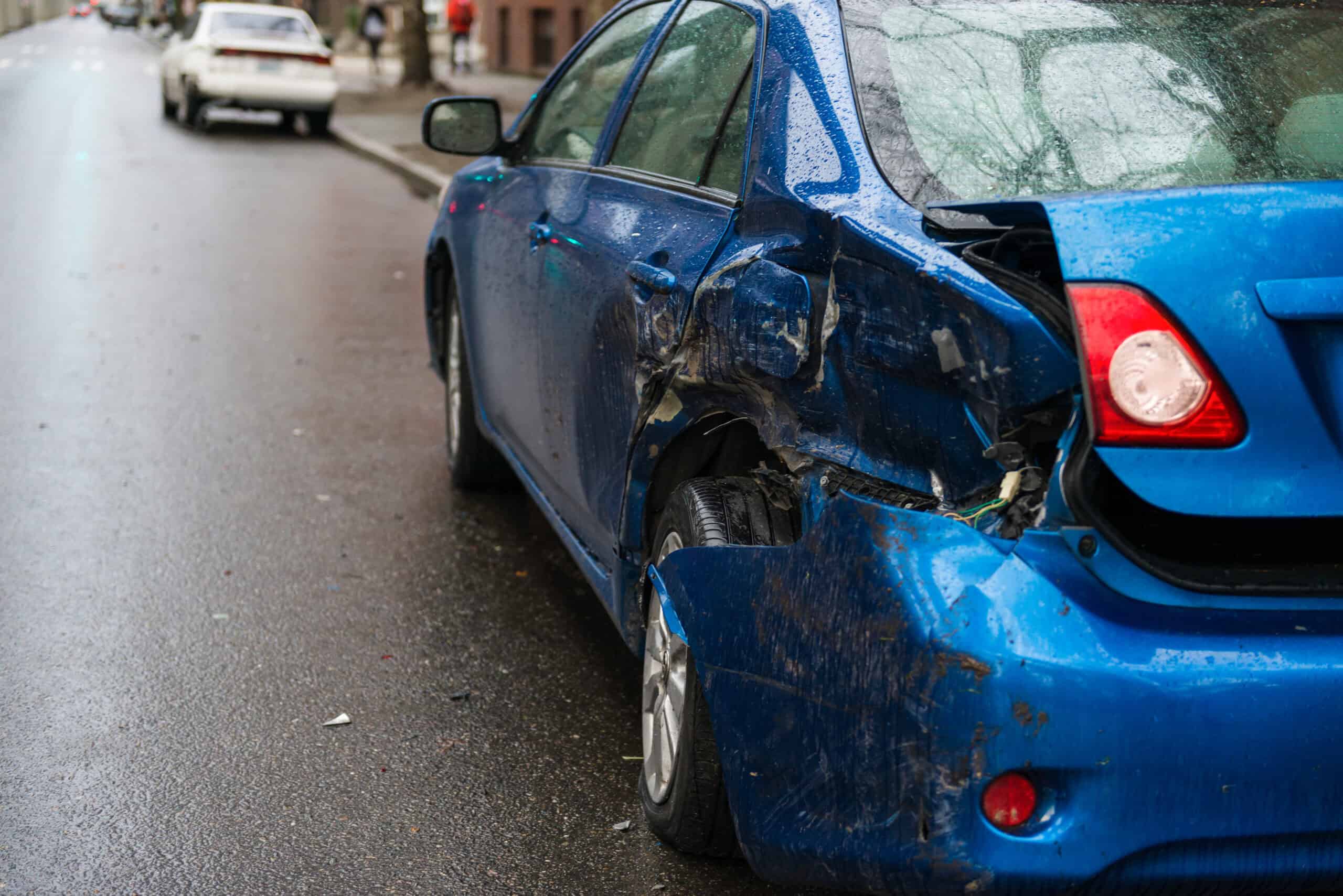 A blue car with side panel damage after a sideswipe accident.