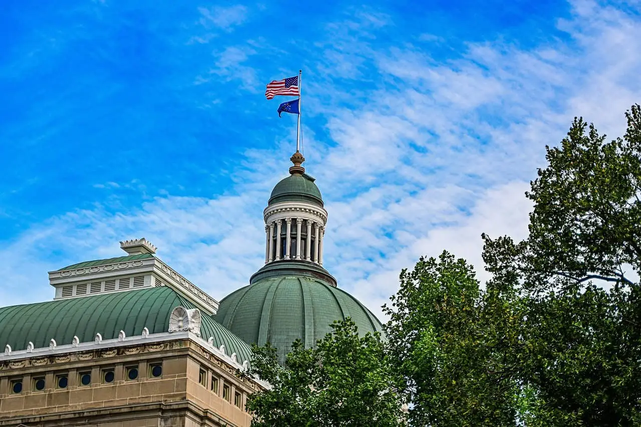 A courthouse in Indianapolis, Indiana with the United States flag and the Indiana state flag flying above.