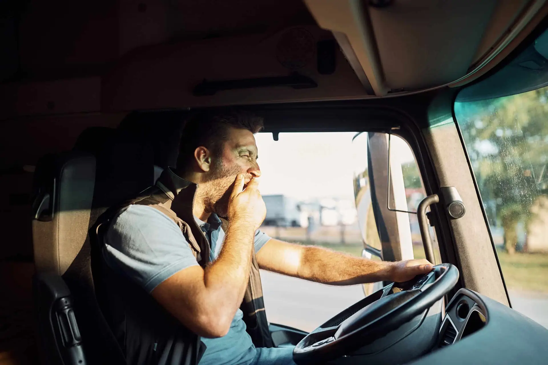 Fatigued driver yawning while driving a truck.