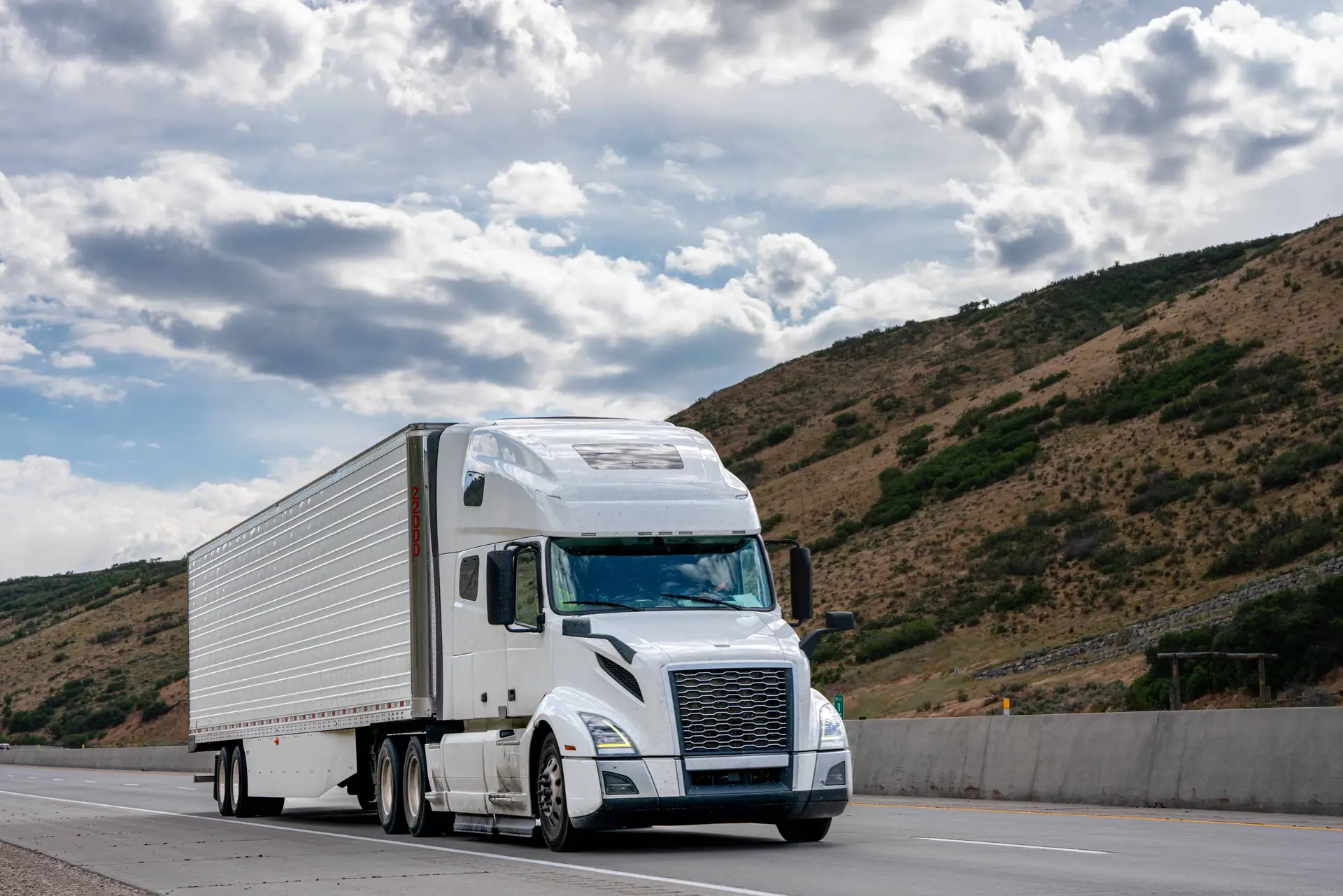A white tractor trailer rolls down the highway