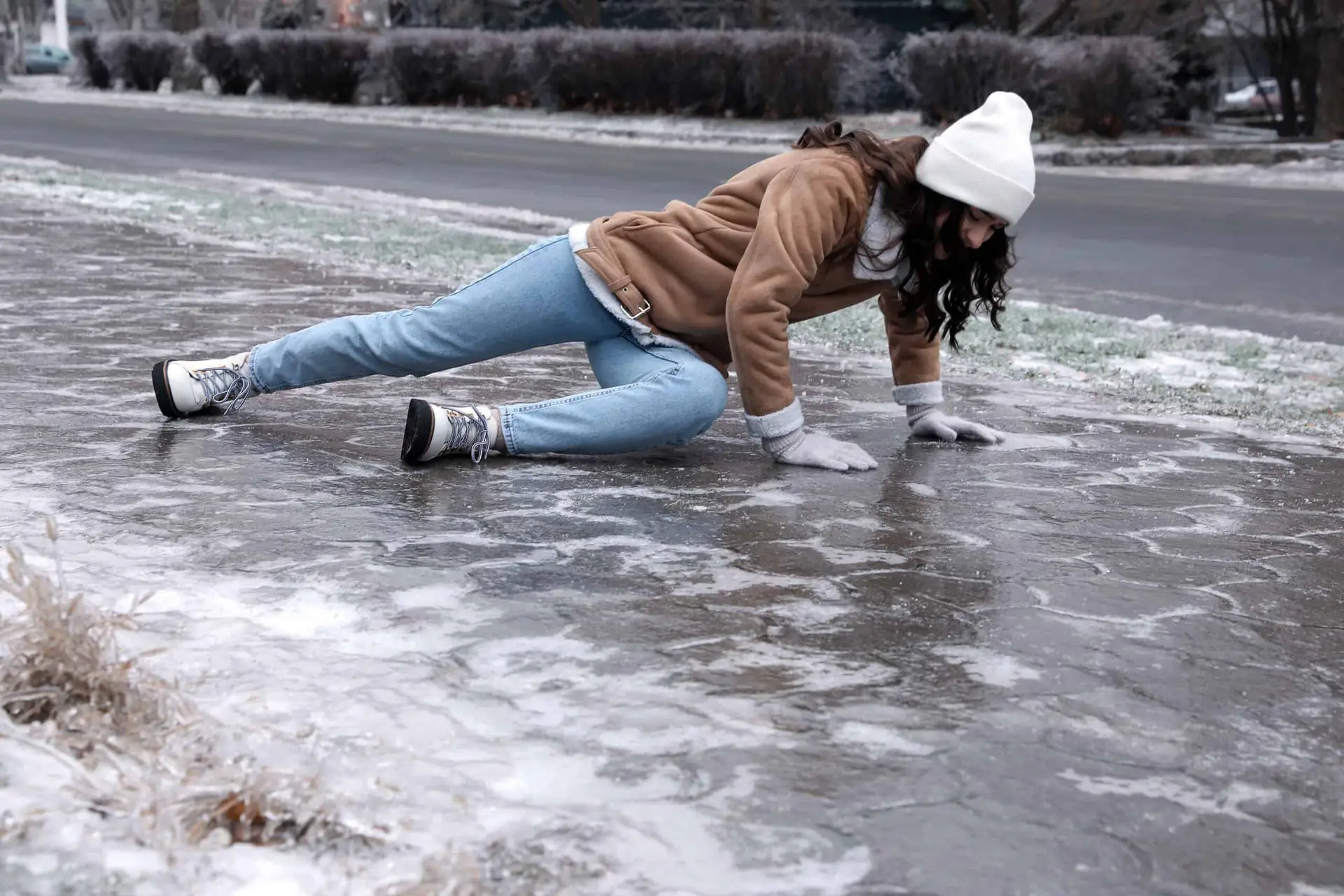 A woman falls to the ground on a sidewalk that is covered in ice, leading to potential slip and fall liability for the property owner.