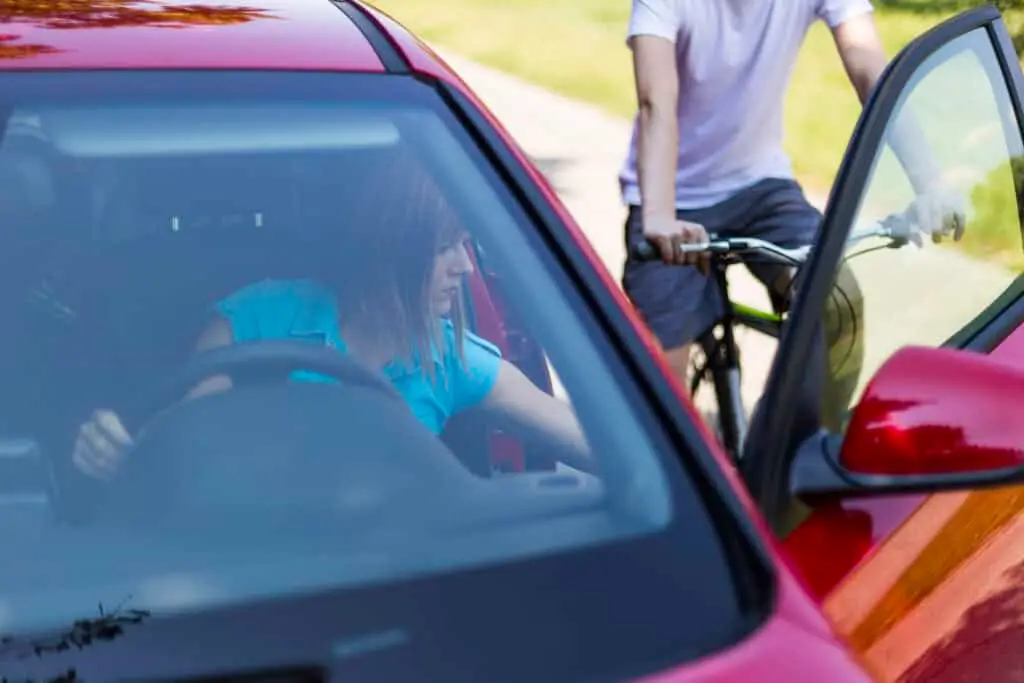 A woman opens her car door into the path of an oncoming cyclist, which is a violation of Indiana state laws.