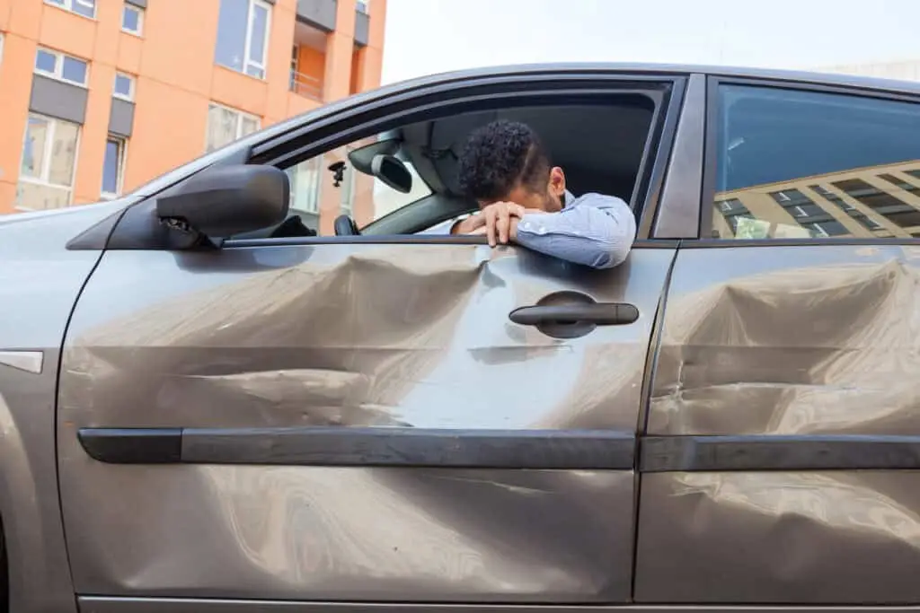 An injured man leans out of his window after a car accident.