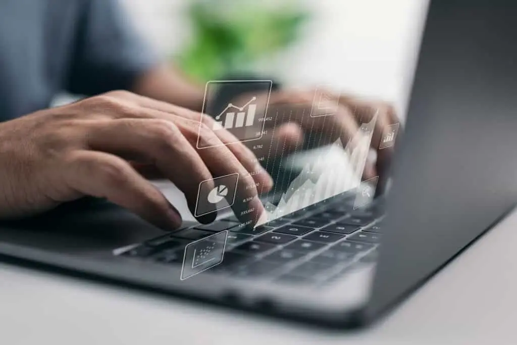A close up view of hands typing on a computer keyboard, creating charts and graphs. 