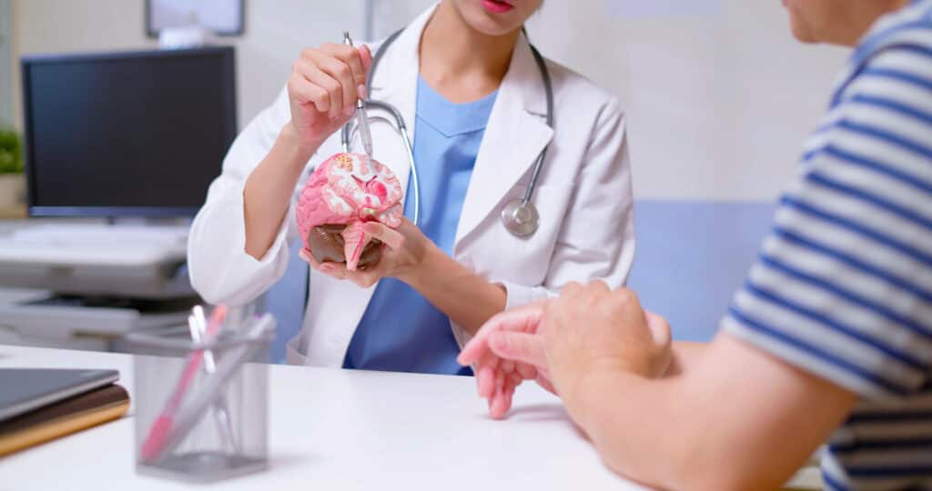 A doctor shows a patient how his brain has been affected on a model of the human brain.