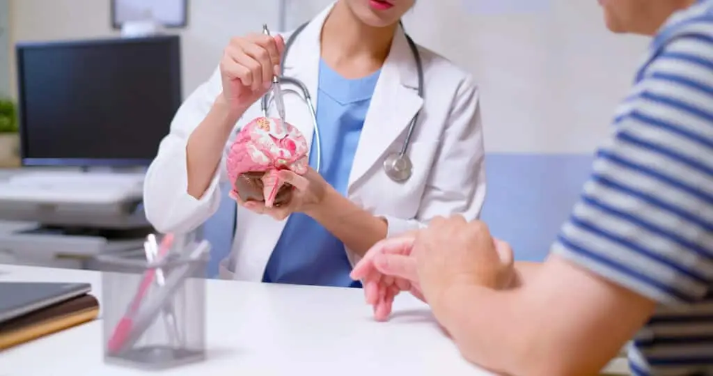 A doctor shows a patient how his brain has been affected on a model of the human brain.