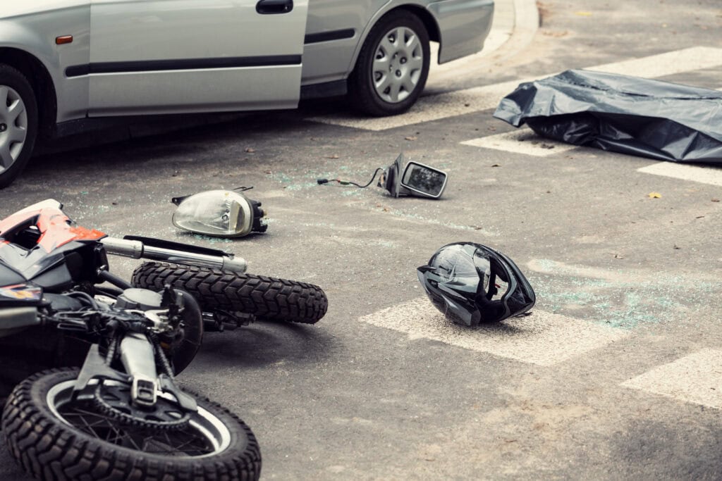 Black helmet and motorcycle on the road after fatal collision with a car.