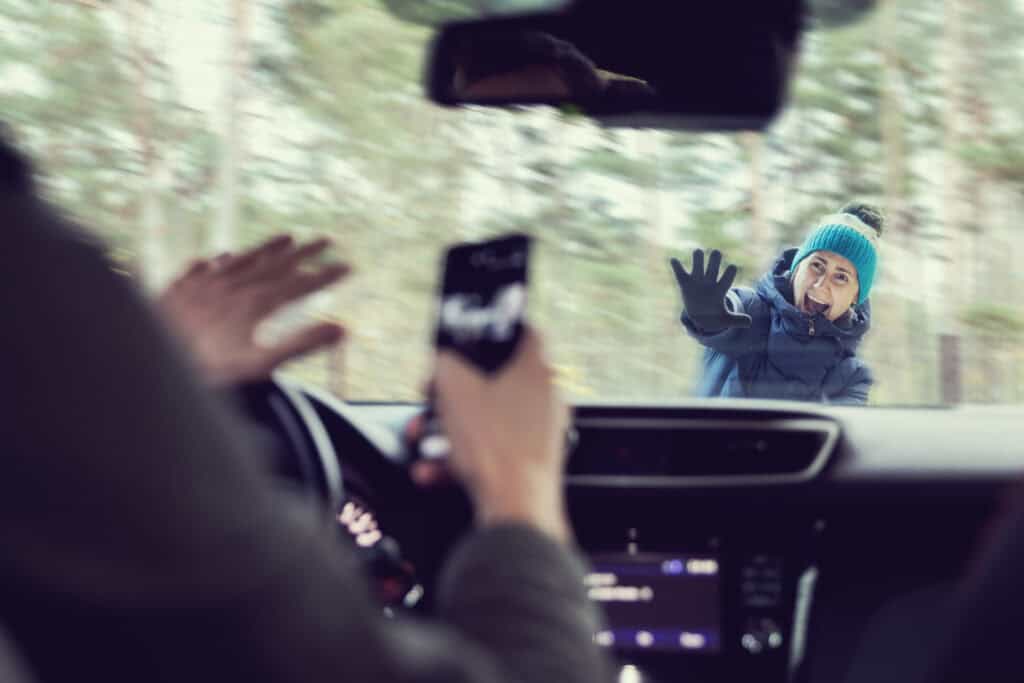 A distracted driver using his phone doesn't see the woman pedestrian that he is about to hit with his car while she crosses the crosswalk.