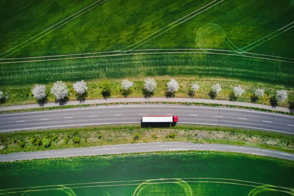 An aerial view of a tractor-trailer traveling down a road.