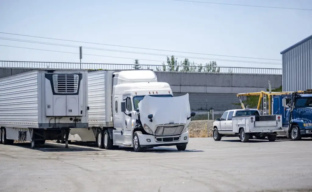 A semi-truck with its hood open sits in a parking lot awaiting inspection after it was involved in a crash on an Indiana highway.