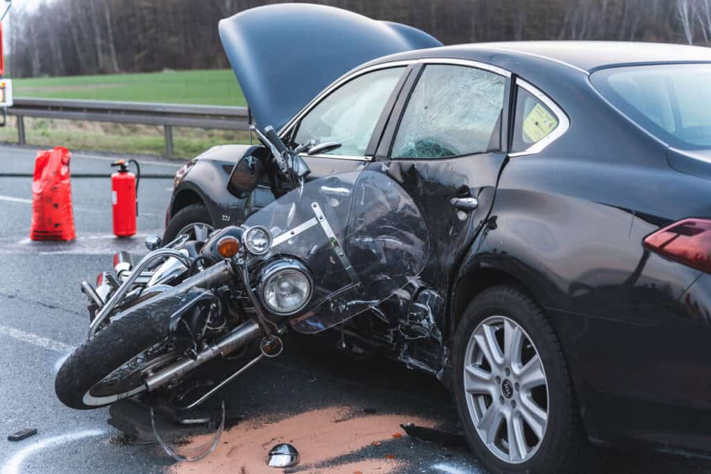 The scene of an accident with a motorcycle having a collision with an automobile, causing damage to both vehicles.