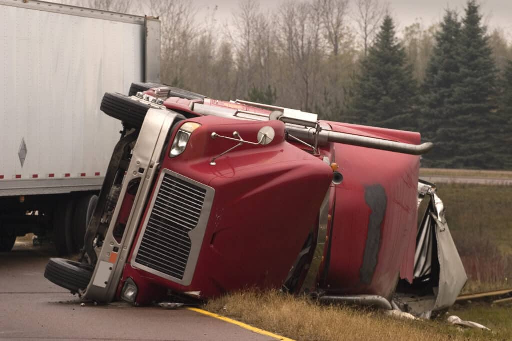 A truck cab lays on its side in the median of the highway after a jackknife truck accident in Evansville, IN.