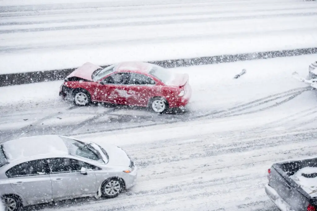 A red car with a damaged front end after an accident in winter conditions on the highway.
