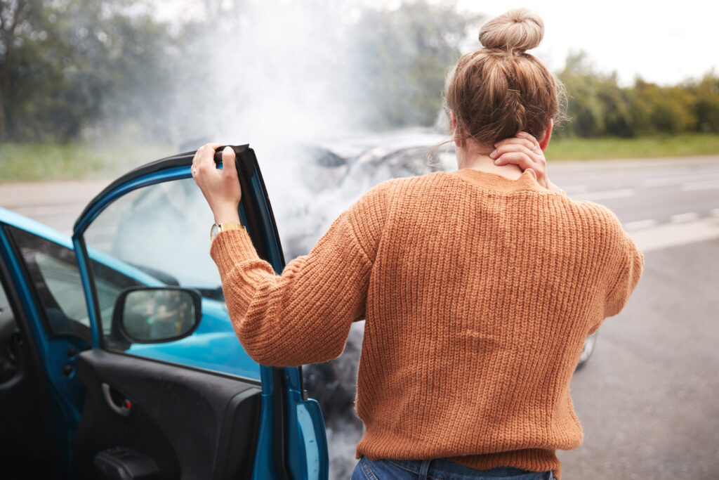 A female passenger exits a car after an accident.