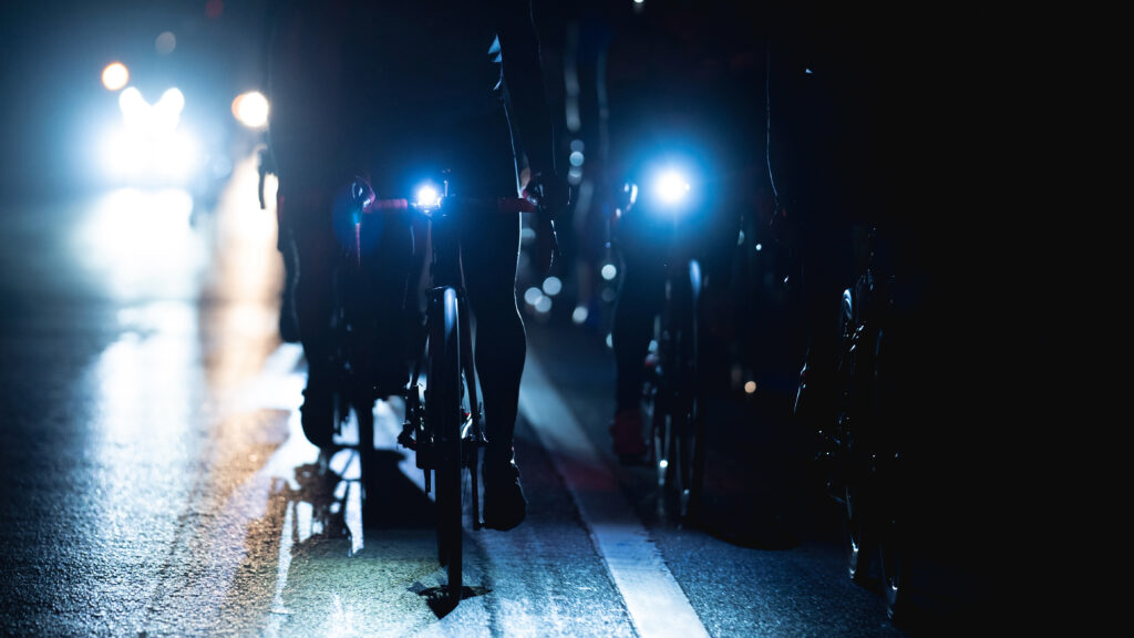 A group of cyclists riding at night.
