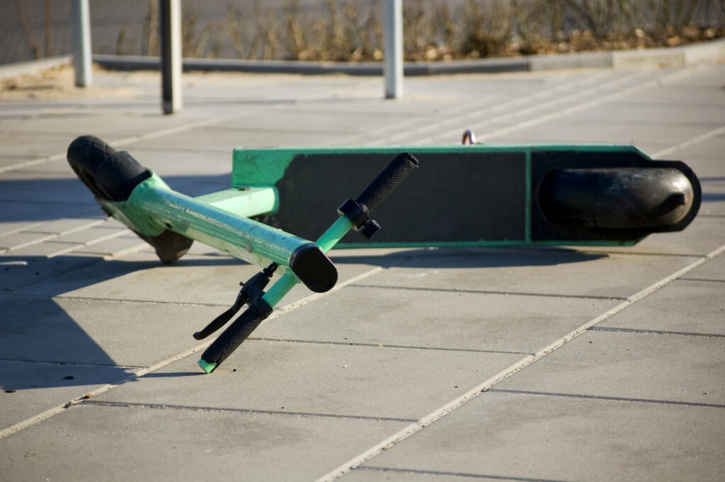 A scooter lies on the pavement after an accident.