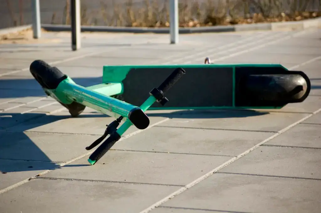 A scooter lies on the pavement after an accident.