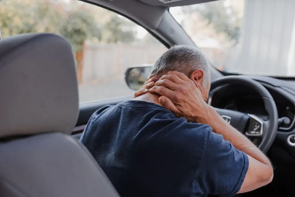 A man holds his neck in pain after a car accident.