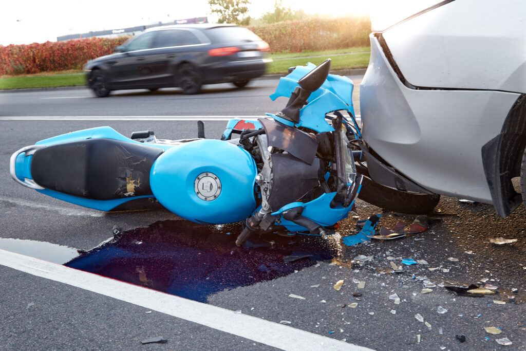 A blue sports motorcycle damaged underneath a car after an accident at high speeds on the highway.