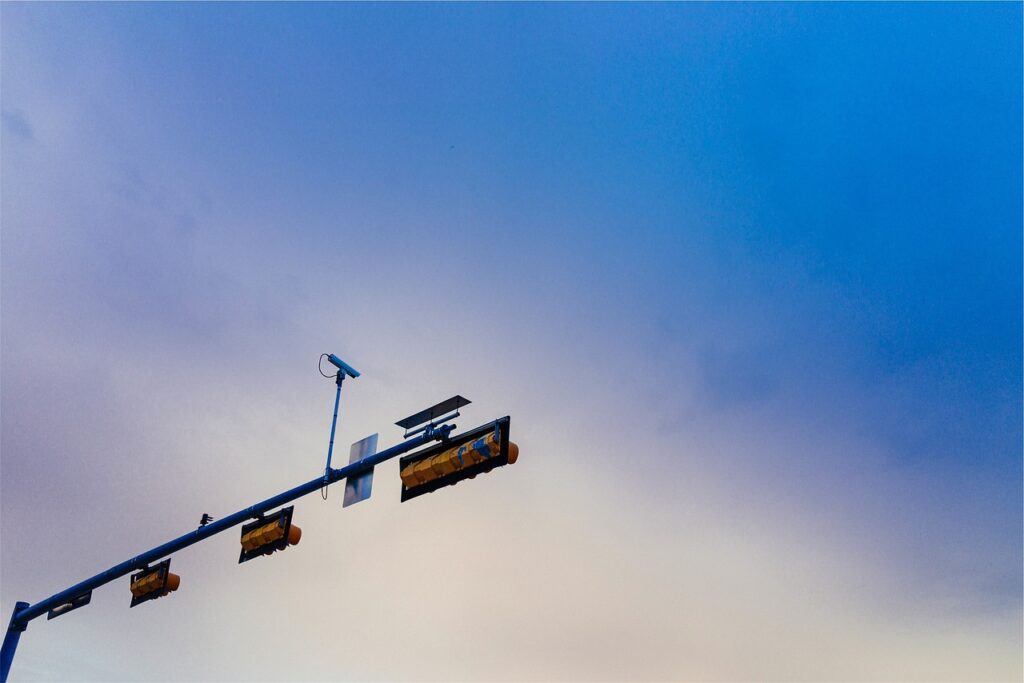 A traffic camera sits on top of a row of stoplights.