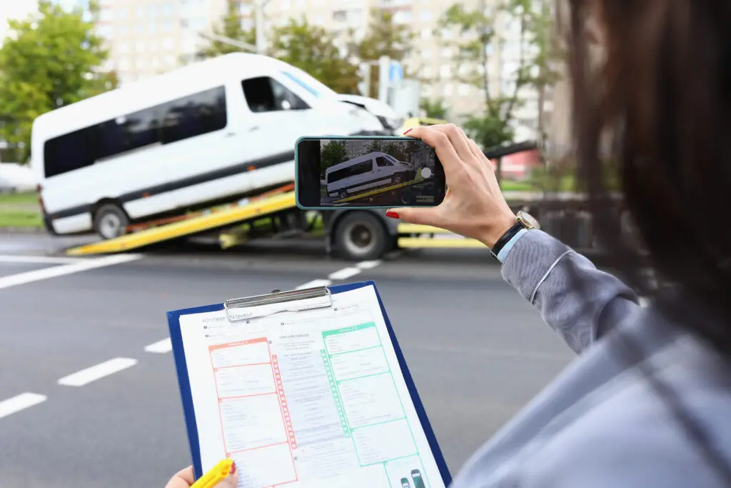 An insurance agent takes pictures of a vehicle that has been in an accident.