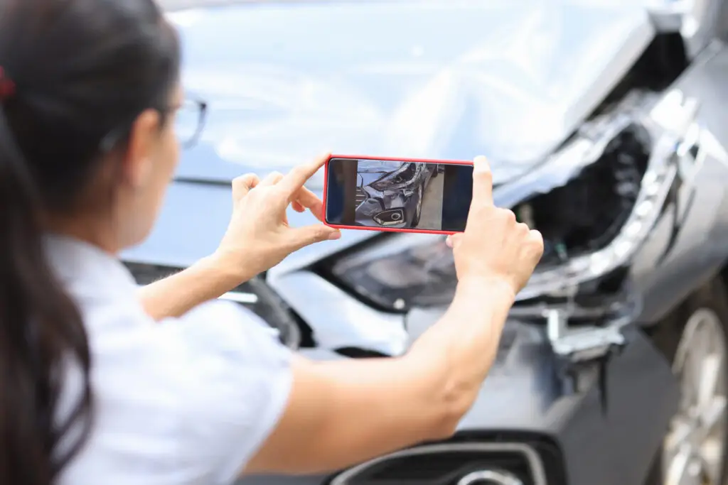 An insurance adjuster takes photos of an accident scene.