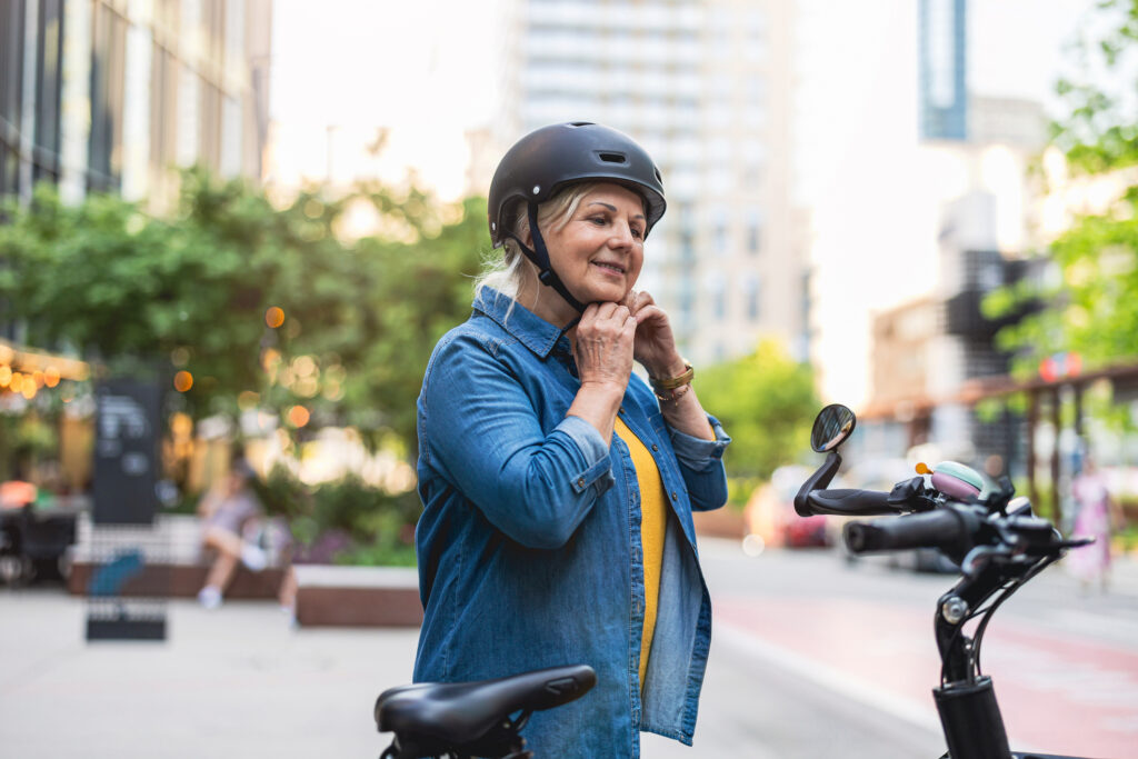 A woman fastens her helmet before she takes her electric bicycle for a ride. 